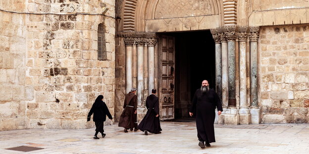 Ein Mönch kommt aus der Tür der Grabeskirche, dahinter eilen zwei Mönche und eine Nonne in die Kirche