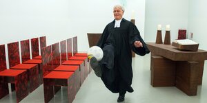 Pfarrer im Talar jongliert mit einem Ball auf dem Fuß