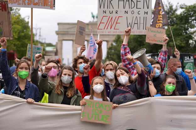 Greta Tunberg vor einer Gruppe Demonstranten mit Schildern