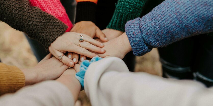 Mehrere Menschen legen ihre Hand über die der jeweils anderen