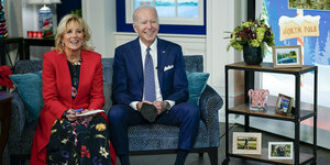 Joe und Jill Biden sitzen auf diner blauen Couch. Daneben ein Beistellwagen mit Bildern und Nippes drauf