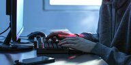 Ein Jugendlicher sitzt an einem Computer und tippt auf der Tastatur