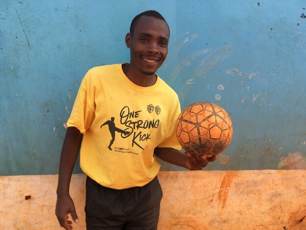 Ein Mann hält einen Fußball und lächelt Ein Mann hält einen Fußball und lächelt
