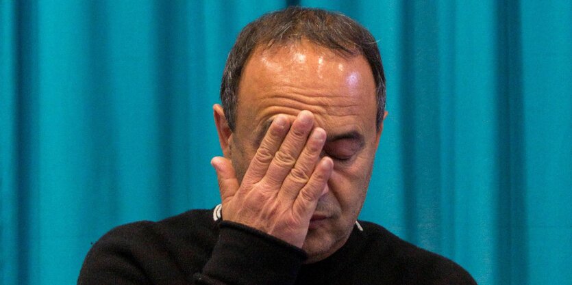 Nahaufnahme von Mimmo Lucano, der eine Hand vors Gesicht hält