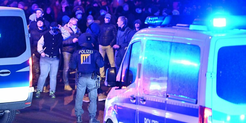 Polizisten und Protestierende in blauem Licht.