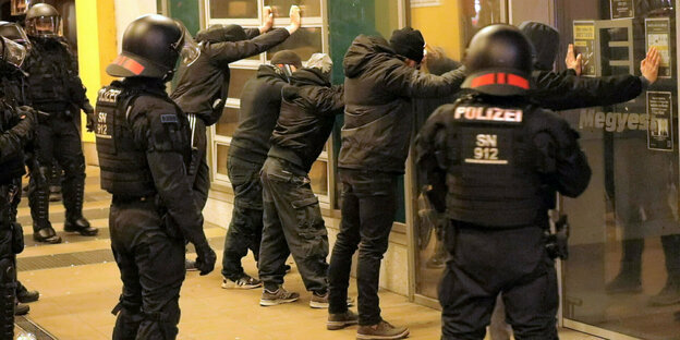 Menschen werden von Polizisten festgehalten. Menschen werden von Polizisten festgehalten.