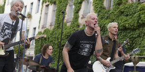 Die Mitglieder der Band Das War Mord bei einem Auftritt auf der Bühne: Der Sänger in der Mitte trägt ein T-Shirt mit der Aufschrift "Radioactivity"