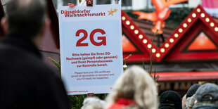 Ein Schild zeigt die 2G-Regel an einem Weihnachtsmarkt an.