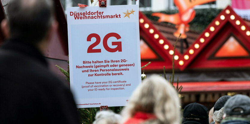 Ein Schild zeigt die 2G-Regel an einem Weihnachtsmarkt an.