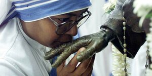 Eine Nonne küsst die Hand einer Statue.