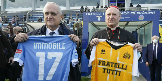 Lazio Präsident Claudio Lotito und ein Kardinal halten Trikots vor die Kamera