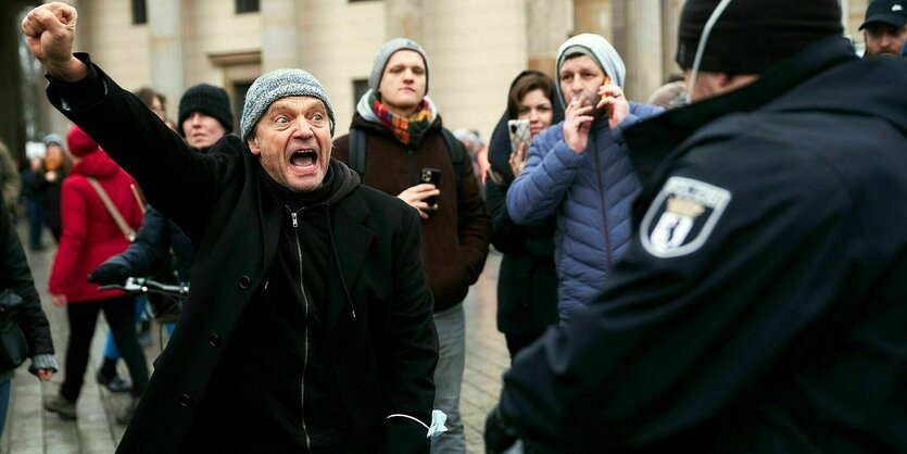 Ein Mann steht einem Polizisten gegenüber und reckt die Faust