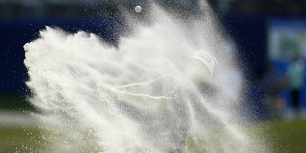 Ein Golfprofi inmitten eine Sandwolke