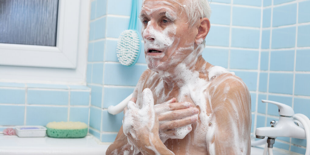 Ein Mann sitzt in der Badewanne und seift sich ein