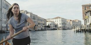 Eine Frau steuert eine Gondel auf dem Canal Grande in Venedig