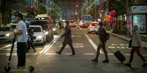 Menschen überqueren eine Hauptstraße in der Madrider Innenstadt