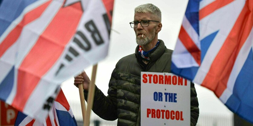 Ein Demonstrant steht zwischen Union Flags und raucht