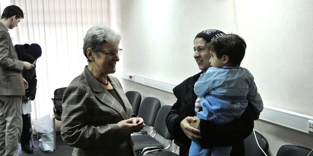 Swetlana Gannuschkina spricht mit einer Frau, die ein Kind auf dem Arm trägt