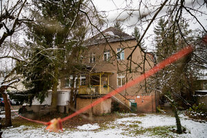 Eine unsanierte Villa, davor Schnee im Garten Eine unsanierte Villa, davor Schnee im Garten