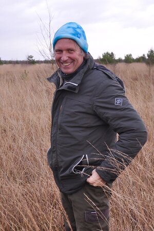 Ein Mann mit blauer Mütze steht in einer Graslandschaft Ein Mann mit blauer Mütze steht in einer Graslandschaft