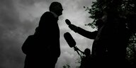 Silhouette von Journalistinnen mit Mikrofonen in der Dämmerung