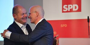 Peter Tschentscher umarmt Olaf Scholz vor einem SPD-Logo
