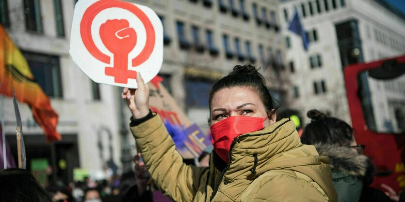 Eine Demonstrantin hält ein Schild hoch mit einem Venussymbol und einer Faust