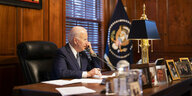 Joe Biden sitzt am Schriebtisch und telefoniert in seiner privaten Residenz