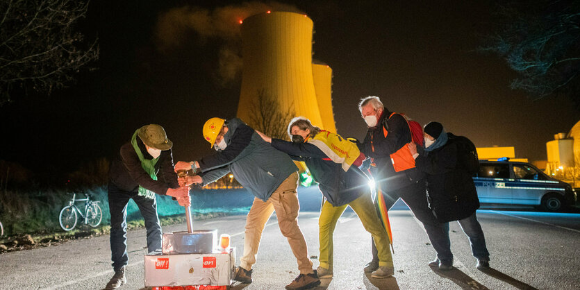 Menschen mit einem sybomlischen Schalter in der NAcht vor Kühltürmen