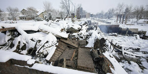 Verkohlte Trümmer von Gebäuden sind von Schnee bedeckt