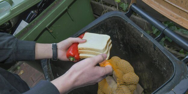 Hände werfen Toastbrot und Kartoffeln in Mülleimer