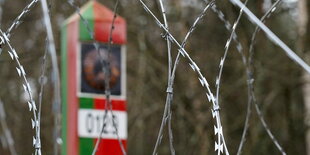 Scharfer Stacheldraht vor einer Grenzmarkierung