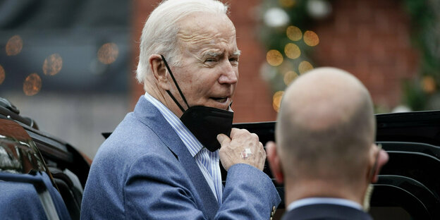 US-Präsident Joe Biden mit angestrengtem Gesicht zieht die schwarze Mund-Nasen-Maske unter das Kinn