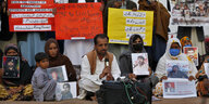 Nasrullah Baluch und protestierende halten Fotos von Verschwundenen in den Händen