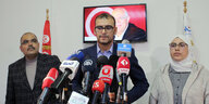 Pressekonferenz im Büro der Islamisten, 3 Menschen stehen vor einem Porträt de Verhafteten