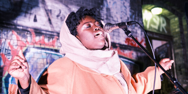 Die Sängerin Savanna Morgan steht im Hof des Kunstraum Bethanien auf der Bühne und singt mit geschlossenen Augen