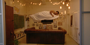 Ein MAnn schwebt schlafend im Raum. Szene aus „The Sleeping Negro“