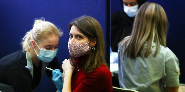 eine junge Frau mit Maske wird geimpft