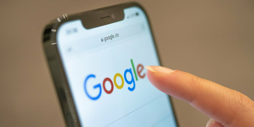 Eine Frau hält ihr Handy in der Hand, auf dem die Google-Seite im Browser zu sehen ist.