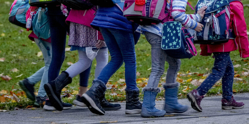 Kinder mit Schulranzen auf einem Weg im Gleichschritt