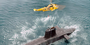 Ein U-Boot ist aufgetaucht, darüber kreist ein Helikopter der eine Person ablässt. Eine Szene aus der Serie Virgil