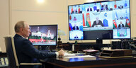 Putin sitzt vor einem Riesenbildschirm während einer Videokonferenz