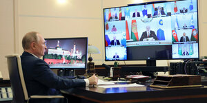 Putin sitzt vor einem Riesenbildschirm während einer Videokonferenz