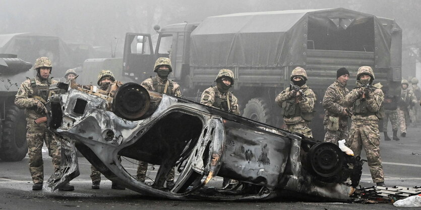 Ein ausgebrannter weißer Transporter liegt auf der Seite, drumherum Nebel, Müll und Trümmer