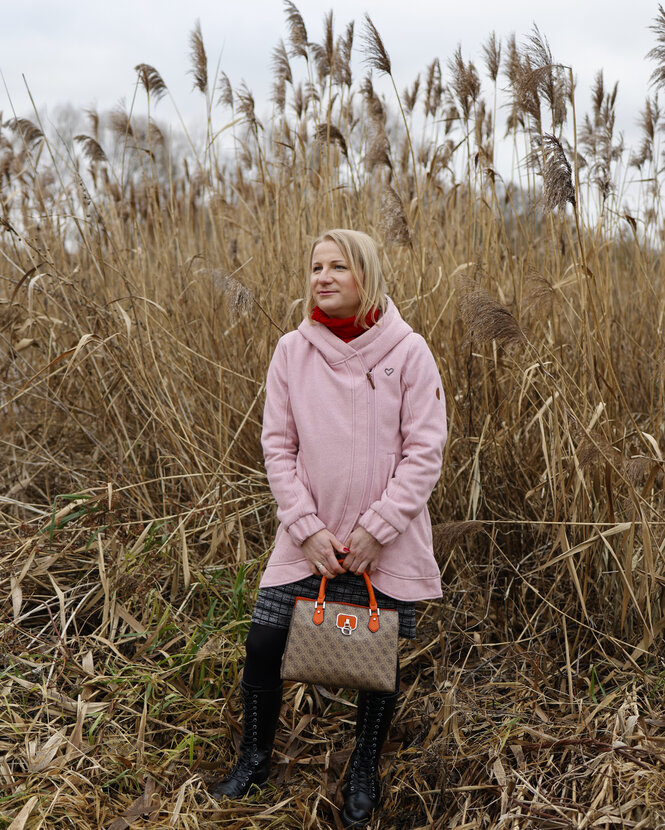 Person in rosa Mantel vor Pflanzen