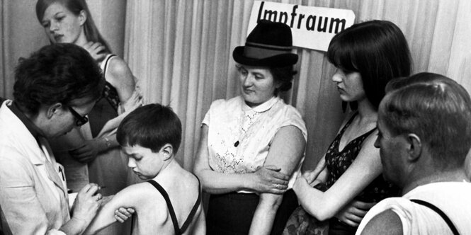 Historisches Bild: Impfung eines Kindes und eine Schlange mit Erwachsenen, die ihre Arme frei gemacht haben