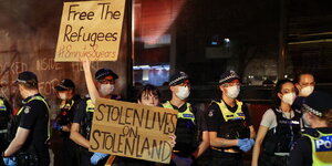 Demonstranten mit Pappschildern vor einem Hotel in Melbourne