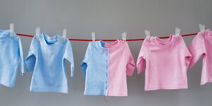 Babyoberteile in rosa und hellblau auf einer Leine in der Mitte sind beide Farben