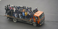 Demonstranten stehen dicht gedrängt auf der Ladefläche eines LKWs und skandieren