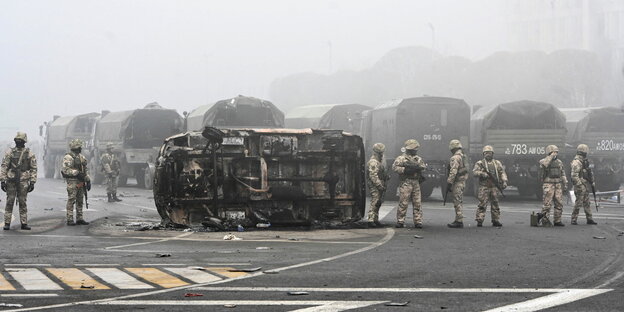 Soldaten stehen bei diesigem Wetter neben einem ungestürzten Fahrzeug
